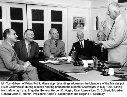 Mr. Tom Gibson of Friars Point, Miss., (standing) addresses the Members of the Mississippi River Commission during a public hearing aboard the steamer Mississippi in May 1954. Sitting from left to right are: Brigadier General Herbert D. Vogel; Rear Admiral Leo O. Colbert; Brigadier General John R. Hardin, President; Albert L. Culbertson; and Eugene F. Salisbury.